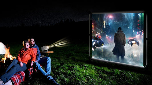 Couple watching a movie outdoors using Vision Beam projector and screen setup at night